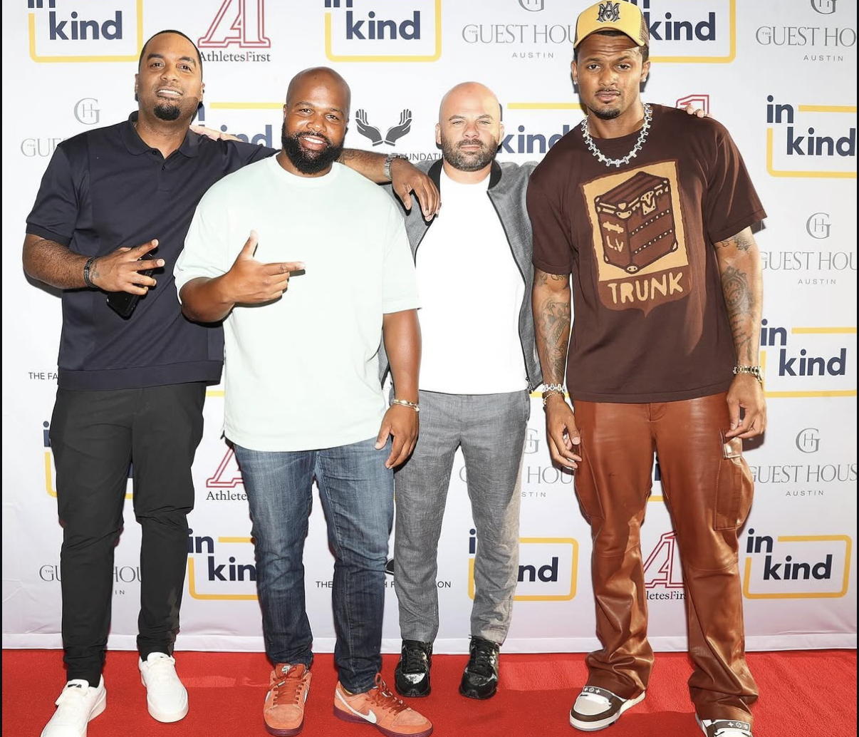 Four men pose together on the red carpet in front of the sponsor backdrop.