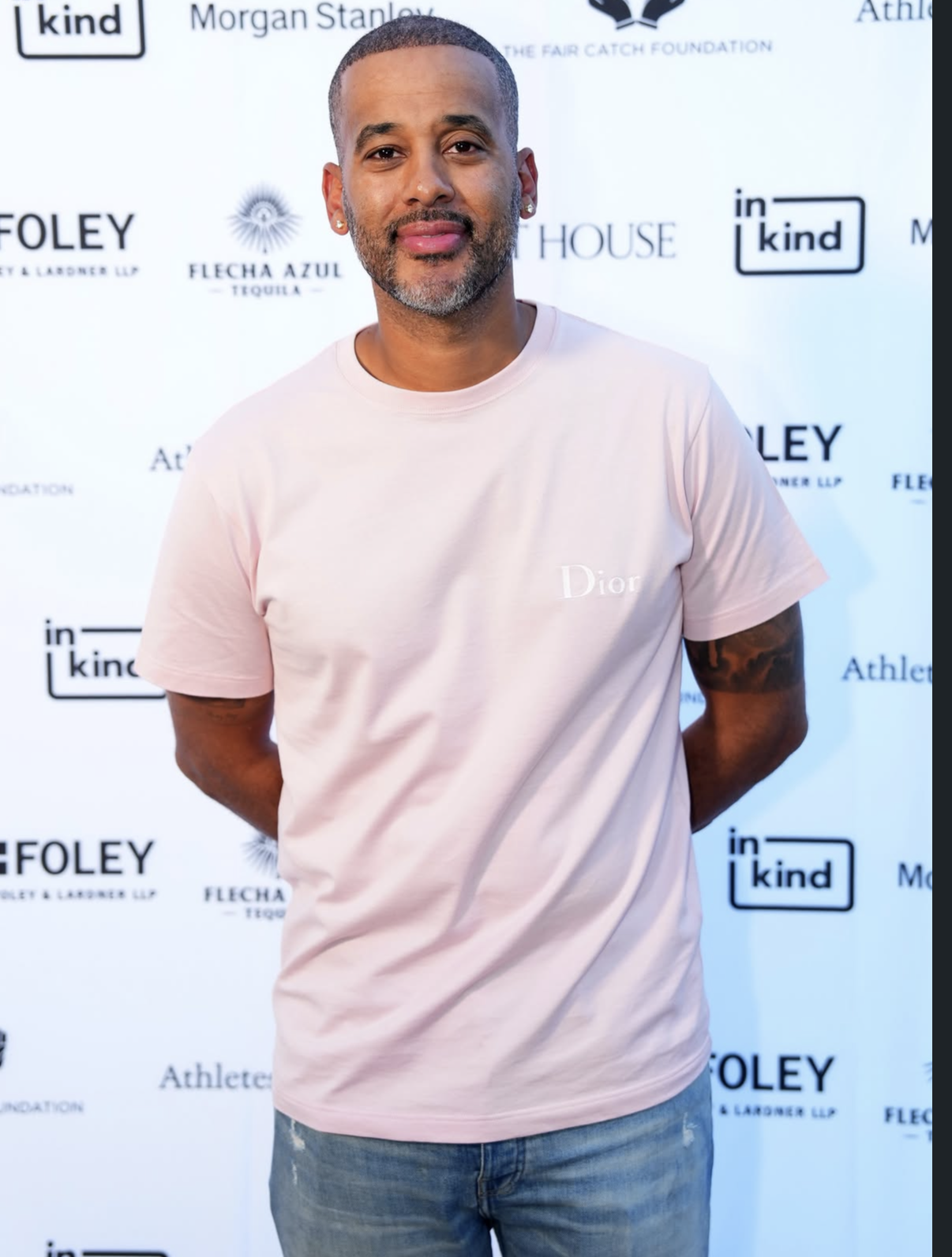 A guest in a pink Dior tee poses on the 2025 red carpet.