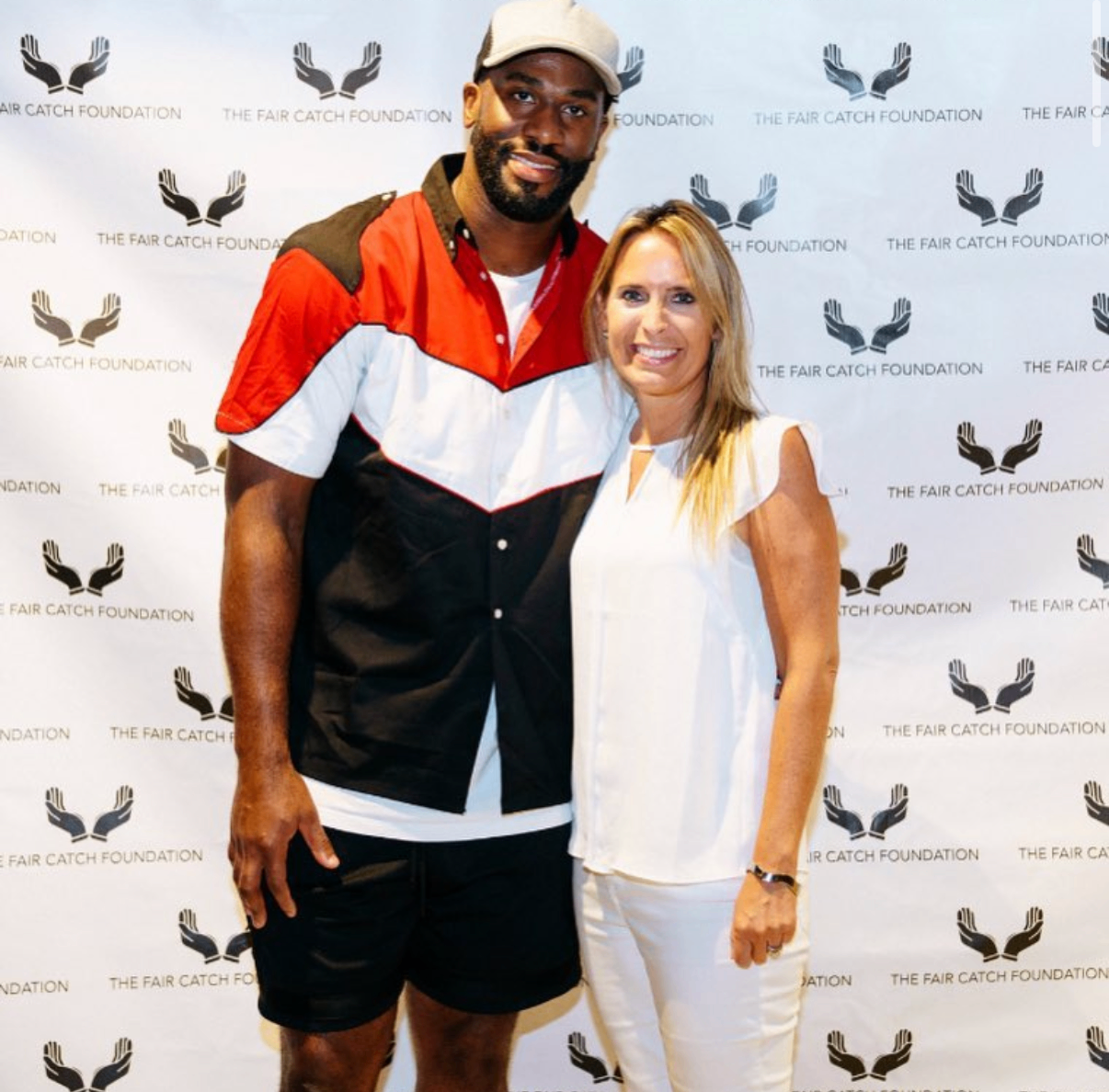 An NFL player poses with a guest in front of the Fair Catch Foundation step-and-repeat at the 2018 Bowl with the Pros Charity Event.
