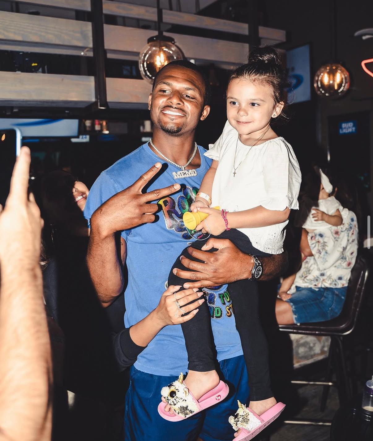 Deshaun Watson holds a young girl and poses for photos with families at the 2019 Bowl with the Pros Charity Event.