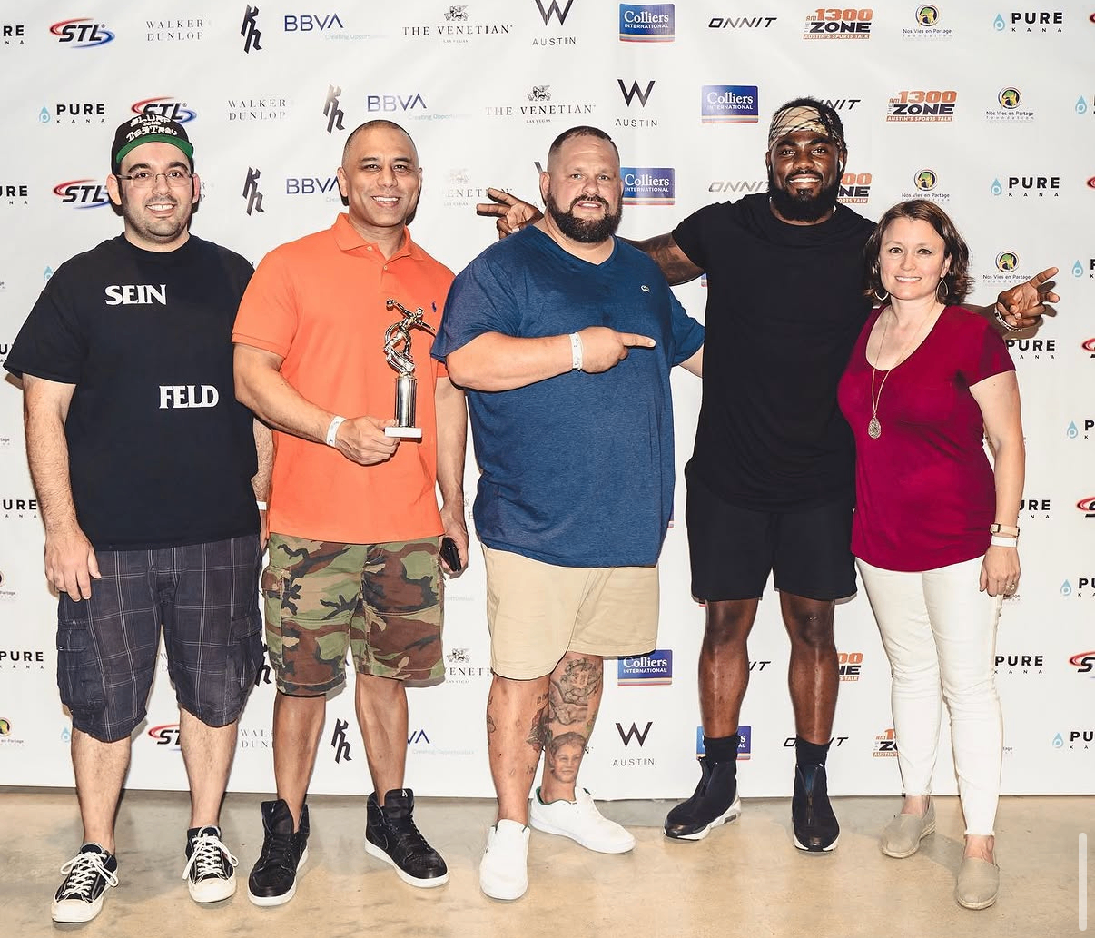 Guests pose with a celebrity bowler and a trophy on the sponsor backdrop at the 2019 Bowl with the Pros Charity Event.