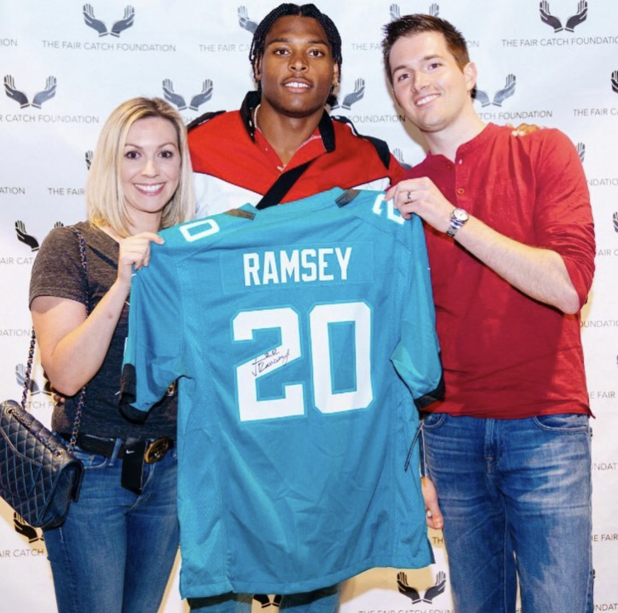 Guests pose with an NFL player holding a signed Ramsey #20 Jaguars jersey at the 2018 Bowl with the Pros Charity Event.