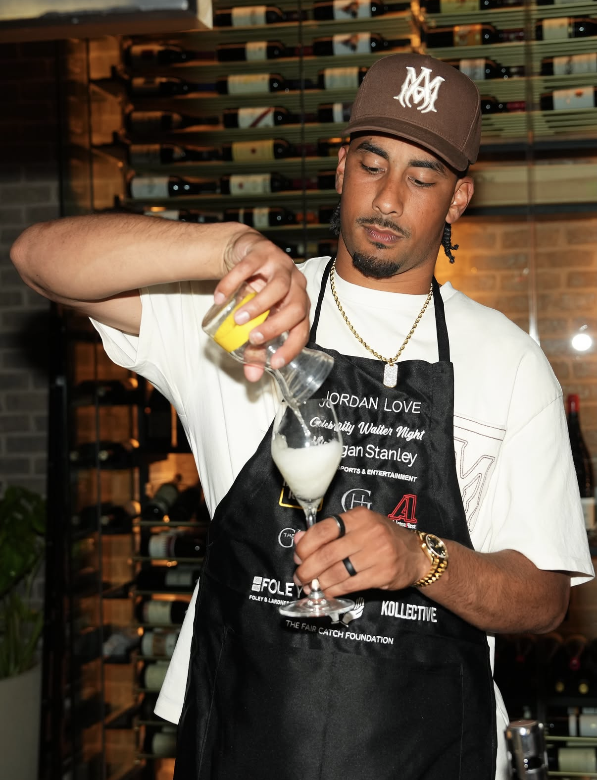 Jordan Love pours a cocktail behind the bar during the 2026 Celebrity Waiter Night.