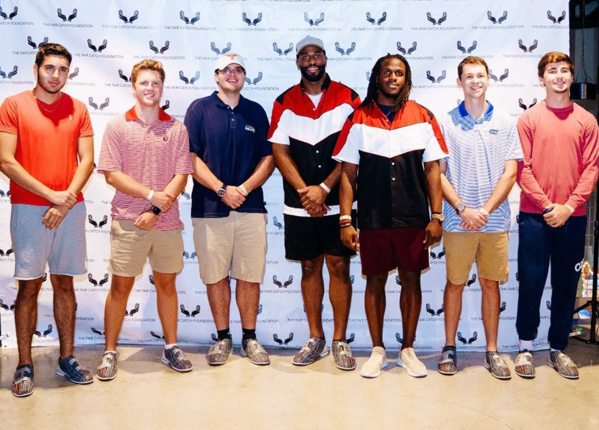 Seven guests pose together on the sponsor step-and-repeat at the 2018 Bowl with the Pros Charity Event.