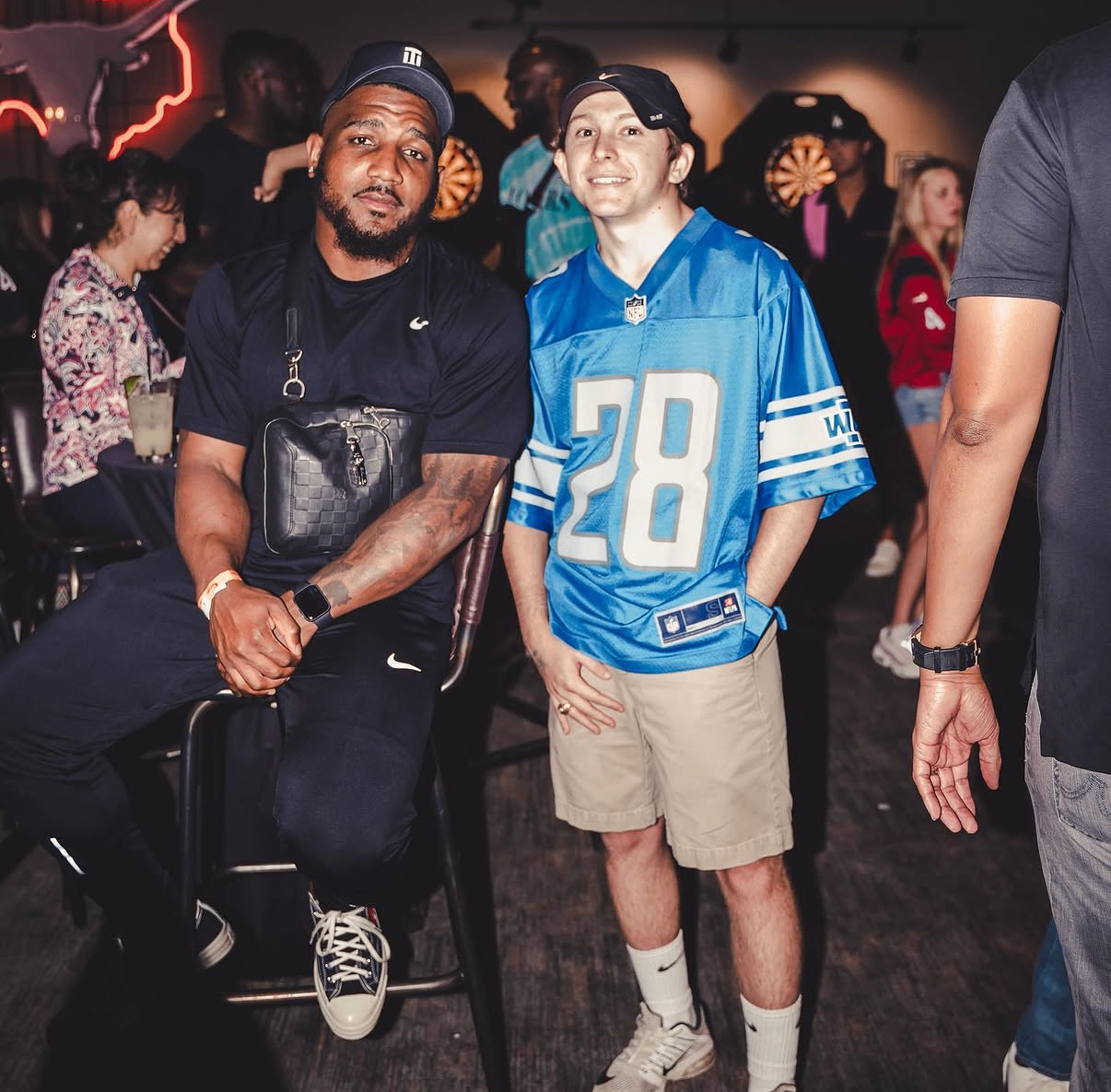Two guests pose together in front of a neon Texas sign at the 2019 Bowl with the Pros Charity Event.