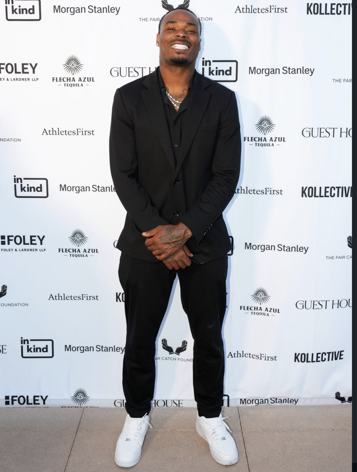 A guest in an all-black suit and fresh white sneakers arrives at Celebrity Waiter Night 2025.