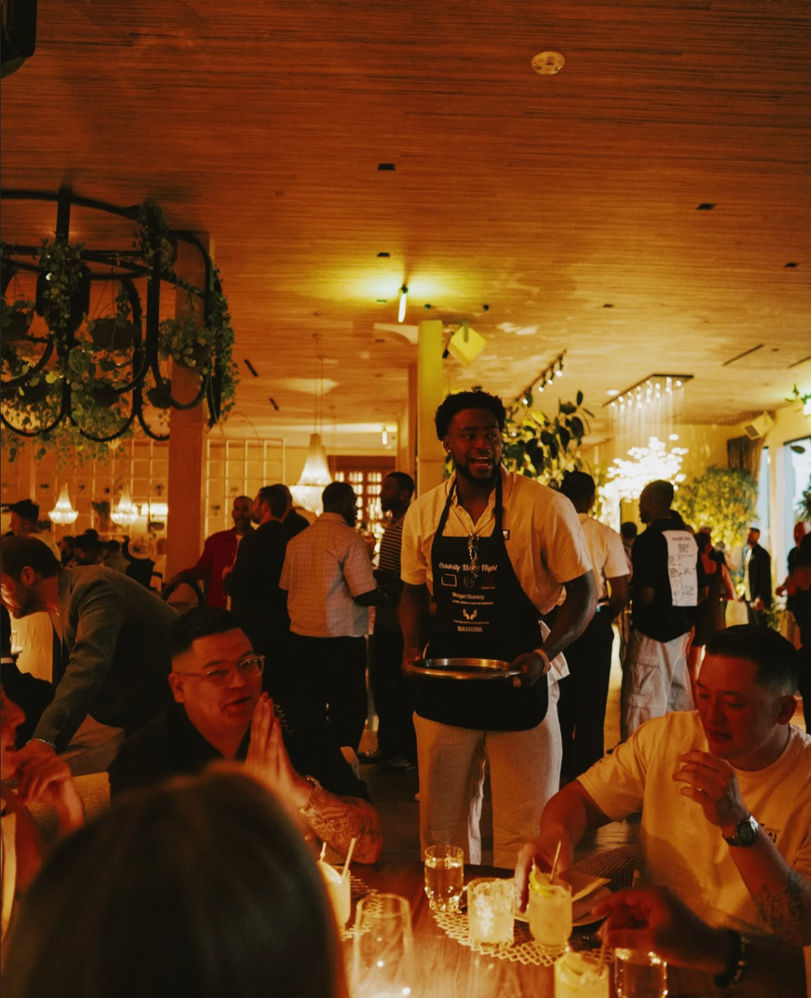 A celebrity waiter carries a tray through the dining room at the 2025 event.