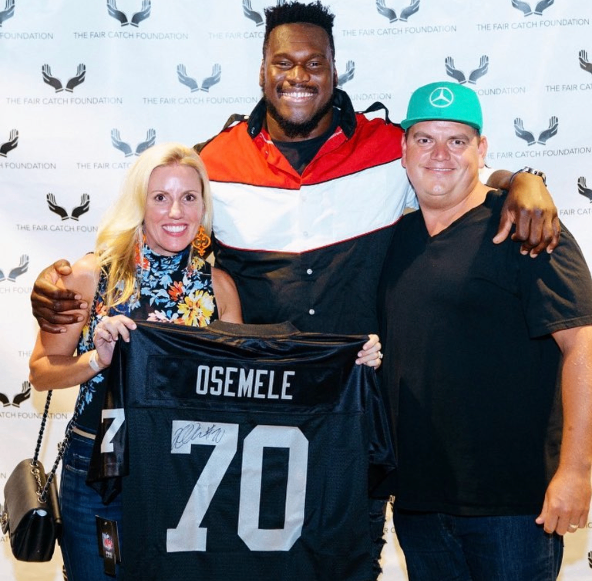Guests hold a signed Osemele #70 jersey with an NFL player at the 2018 Bowl with the Pros Charity Event.