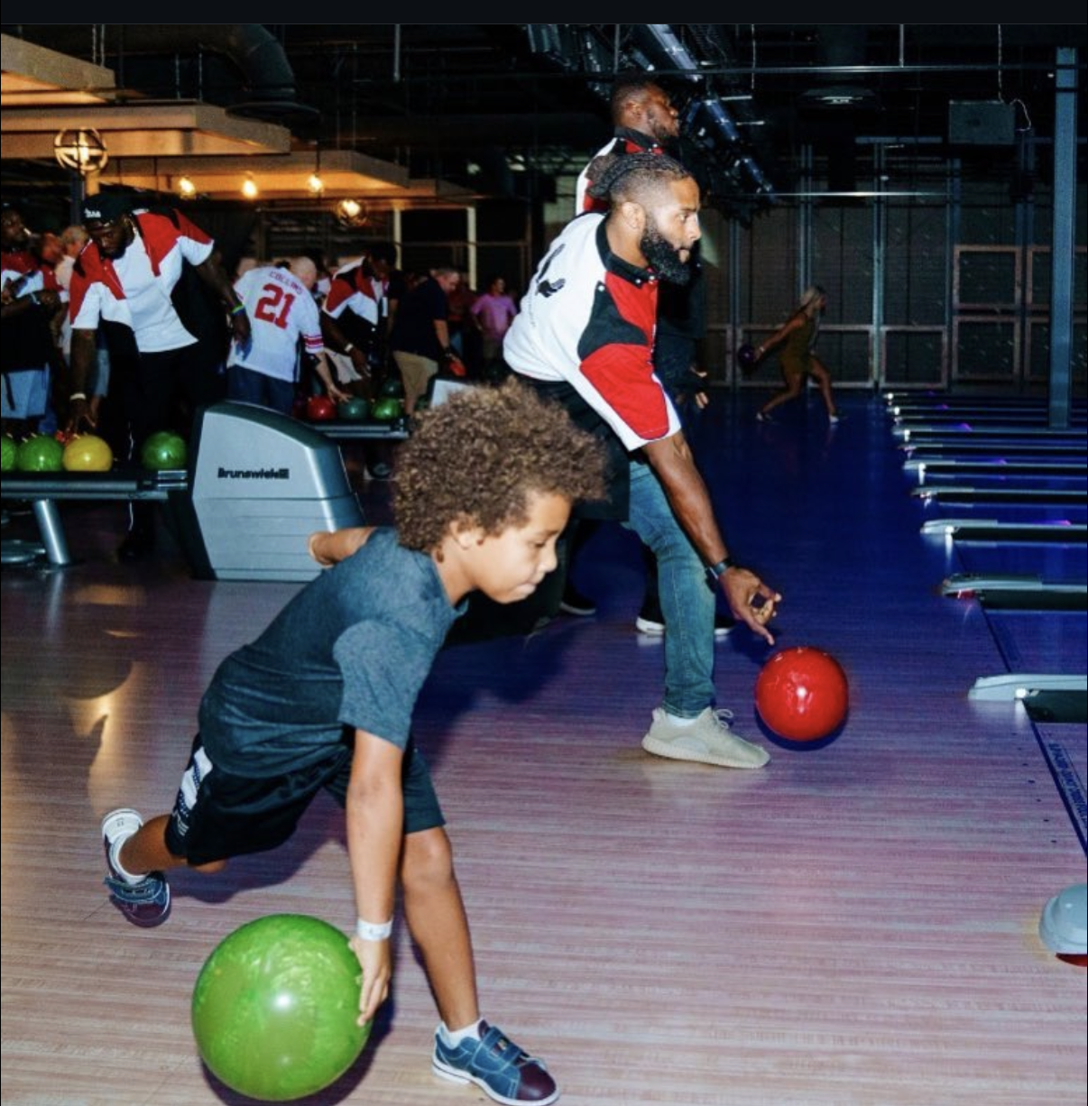 A young bowler and an NFL player roll their balls down neon-lit lanes at the 2018 Bowl with the Pros Charity Event.