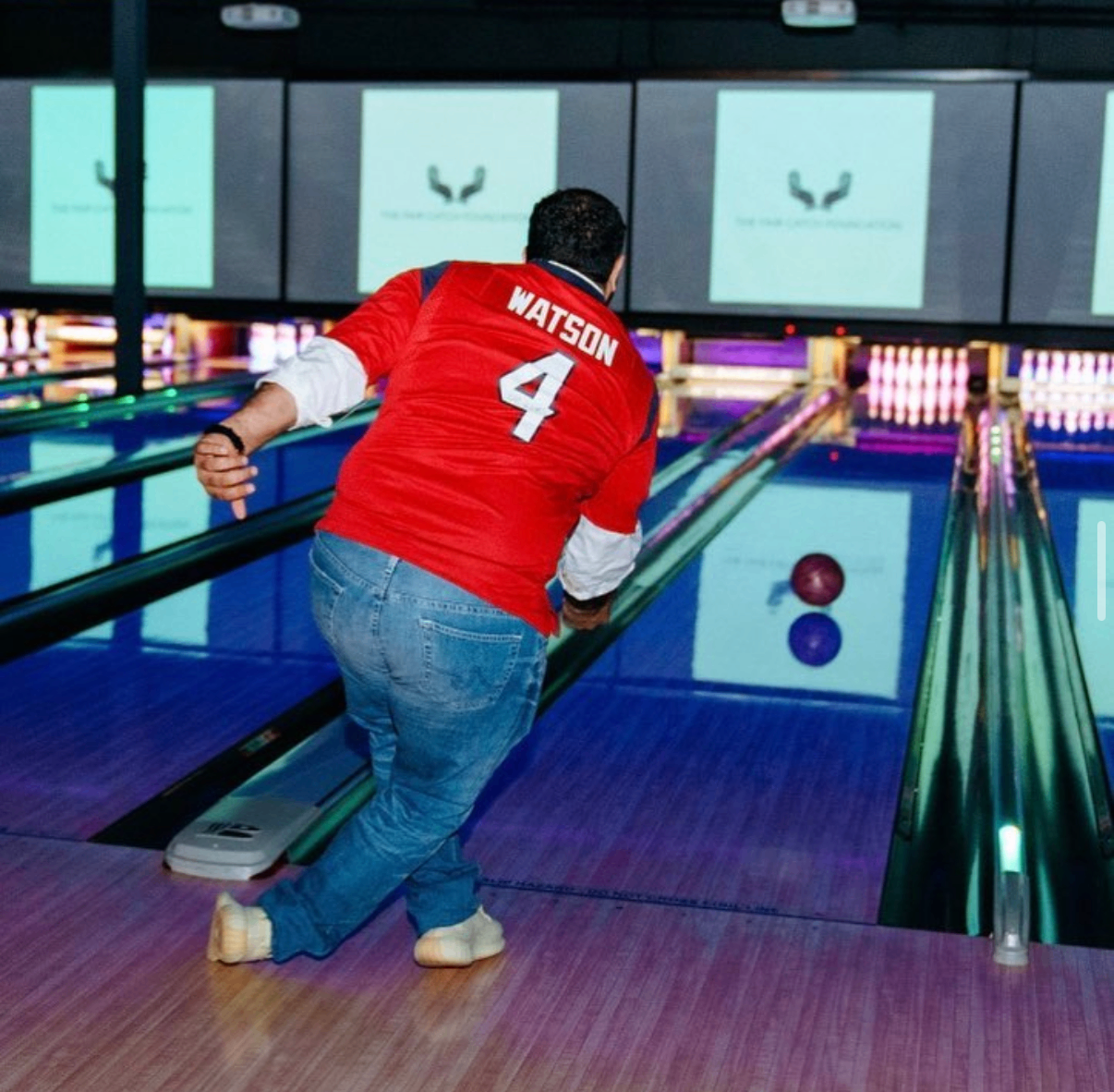 A bowler in a red football jersey rolls a purple ball down the lane at the 2018 Bowl with the Pros Charity Event.
