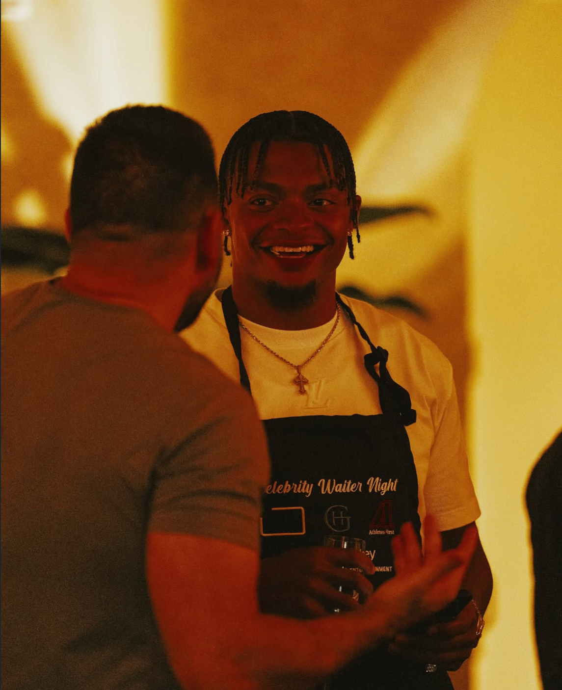 A smiling celebrity waiter shares a moment with a guest during the 2025 event.