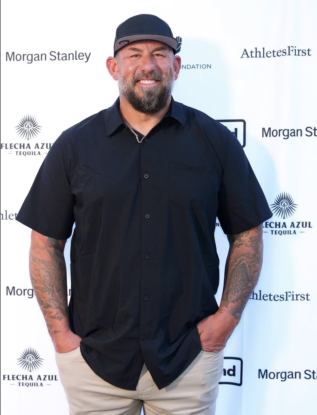 A guest smiles for a portrait at the 2026 Celebrity Waiter Night sponsor wall.