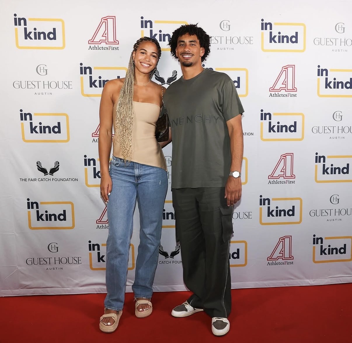 A couple poses on the red carpet in front of the sponsor wall at the 2026 Celebrity Waiter Night.