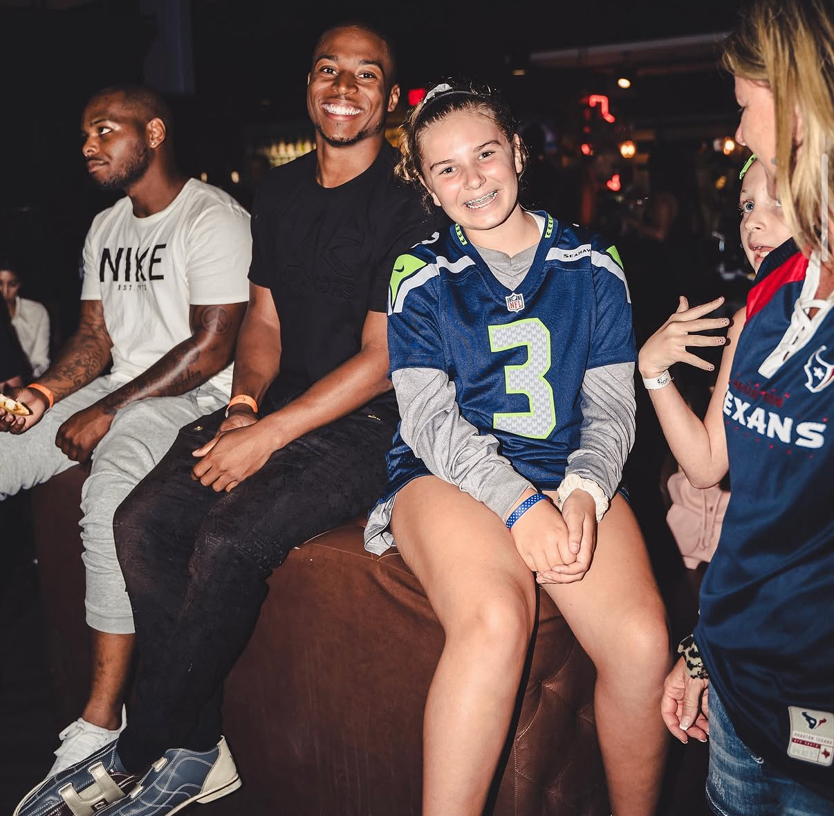 A celebrity player smiles beside a young Seahawks fan on the event floor at the 2019 Bowl with the Pros Charity Event.
