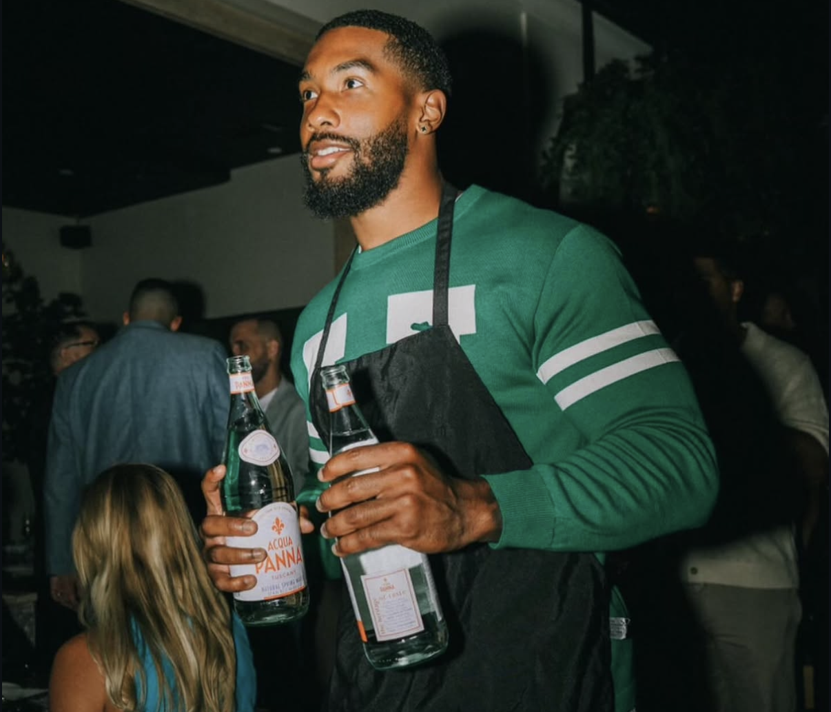 An NFL player in a Celebrity Waiter Night apron greeting guests at the table.