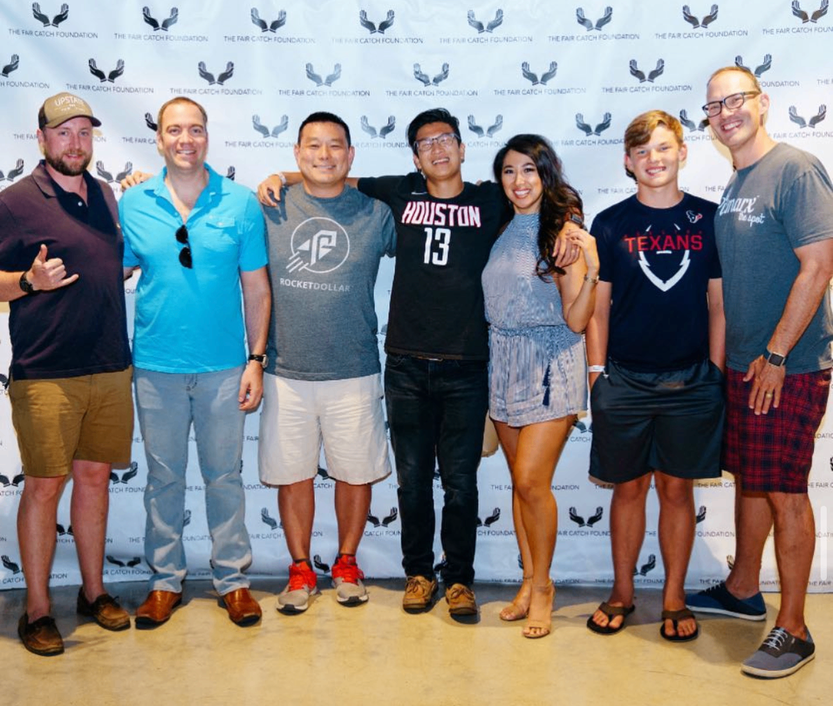 A group of friends and family pose together at the 2018 Bowl with the Pros Charity Event backdrop.