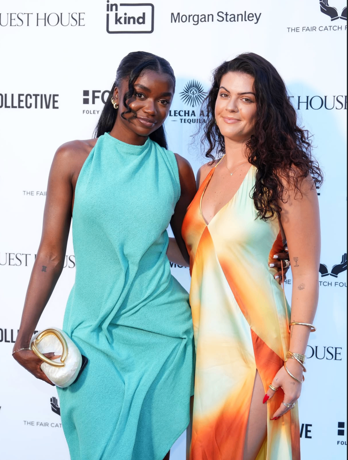 Two guests in vibrant summer dresses pose together on the 2025 red carpet.